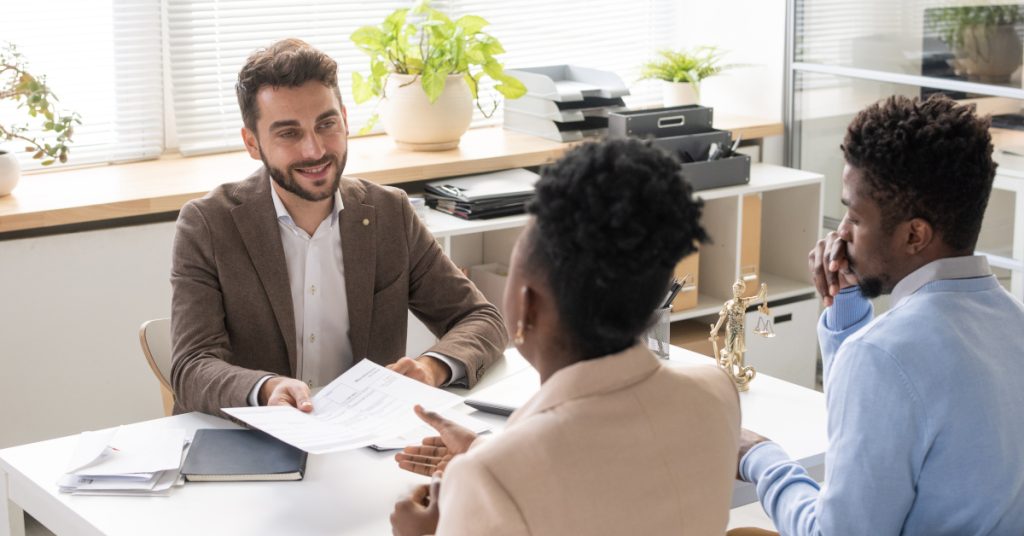 A lawyer hands closing documents to a couple buying a home.